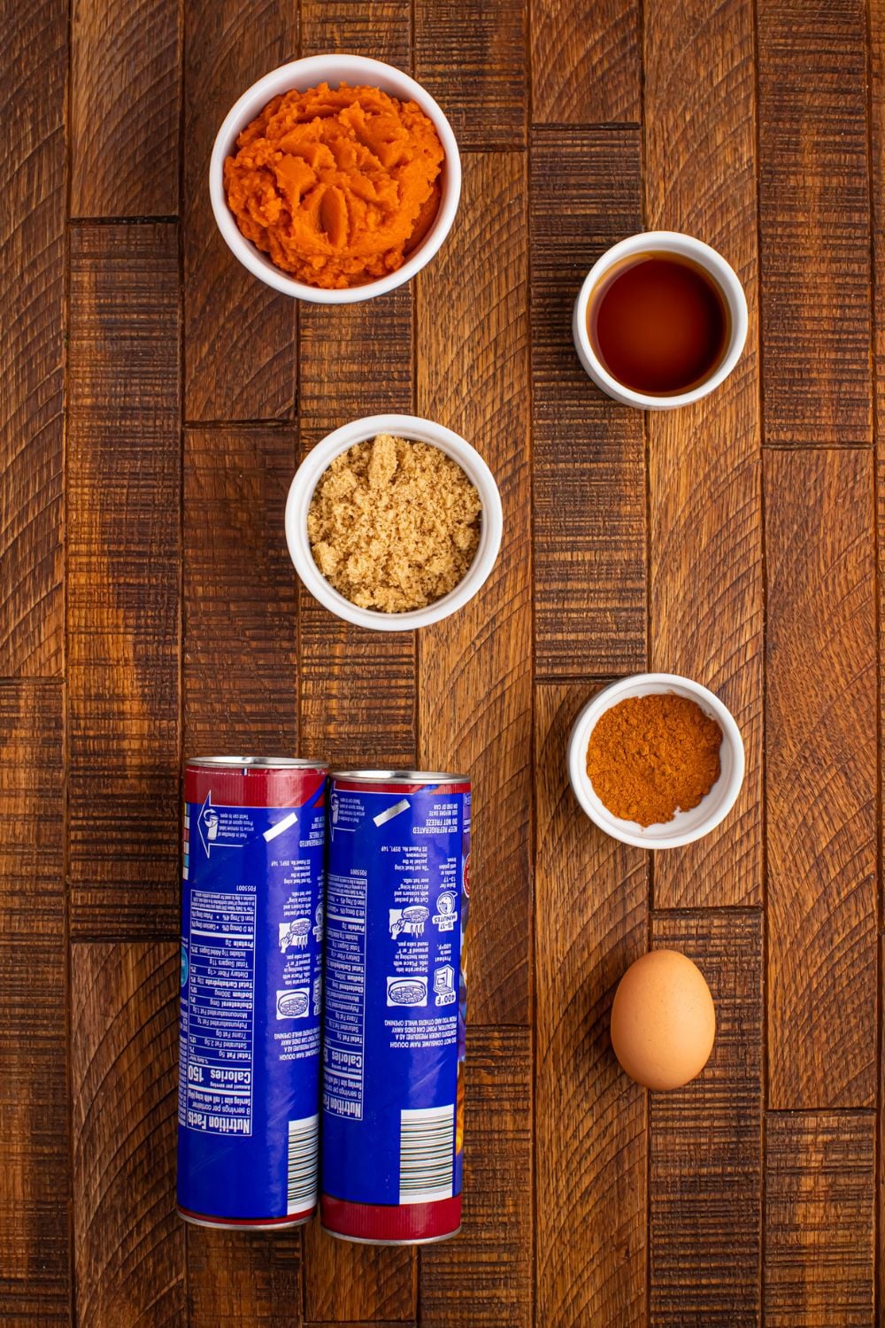 ingredients for Pumpkin Pie Cinnamon Roll Cups on table: canned cinnamon rolls, pumpkin puree, brown sugar, egg, vanilla, pumpkin spice seasoning