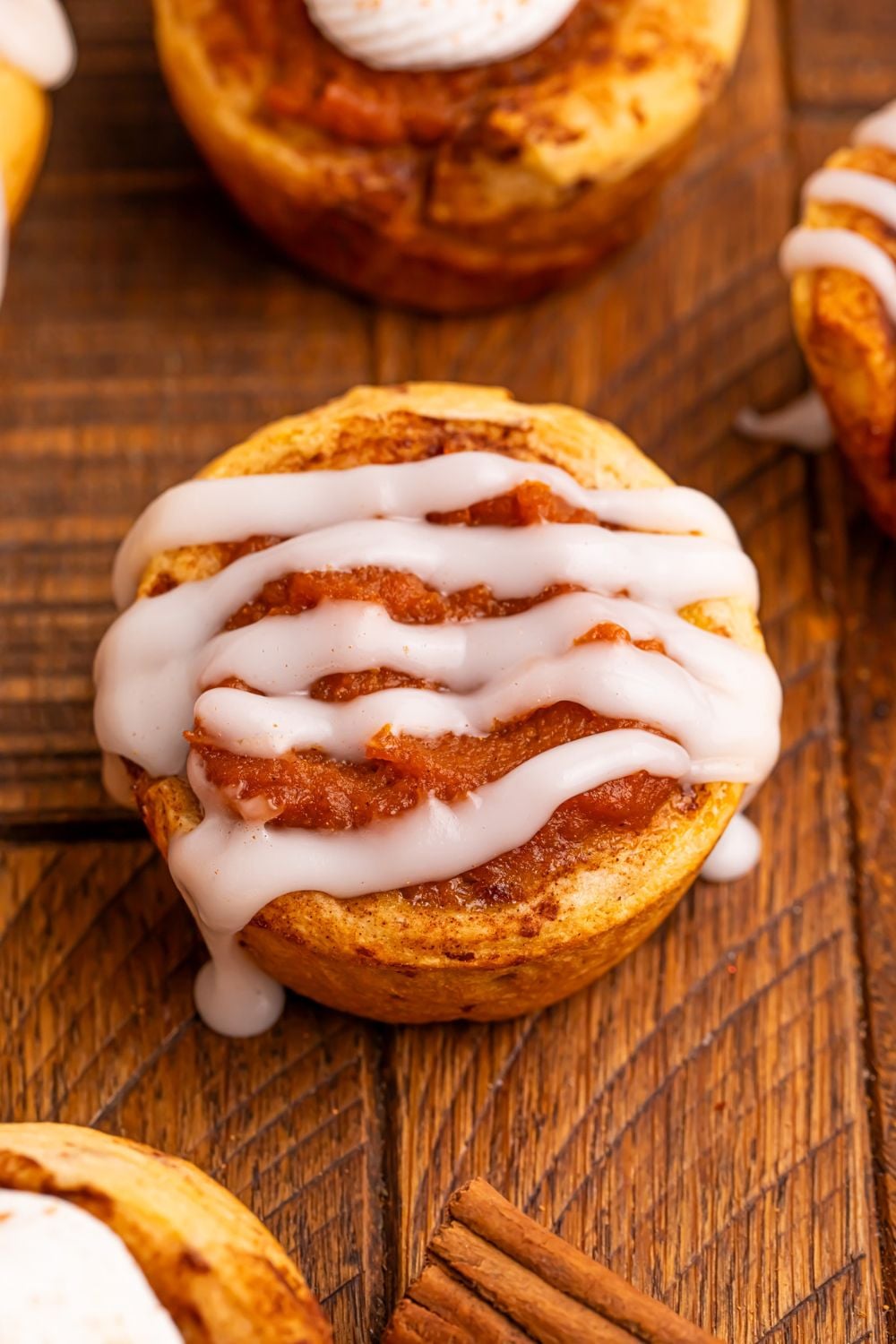 Pumpkin Pie Cinnamon Roll Cup on table with a icing drizzled over the top