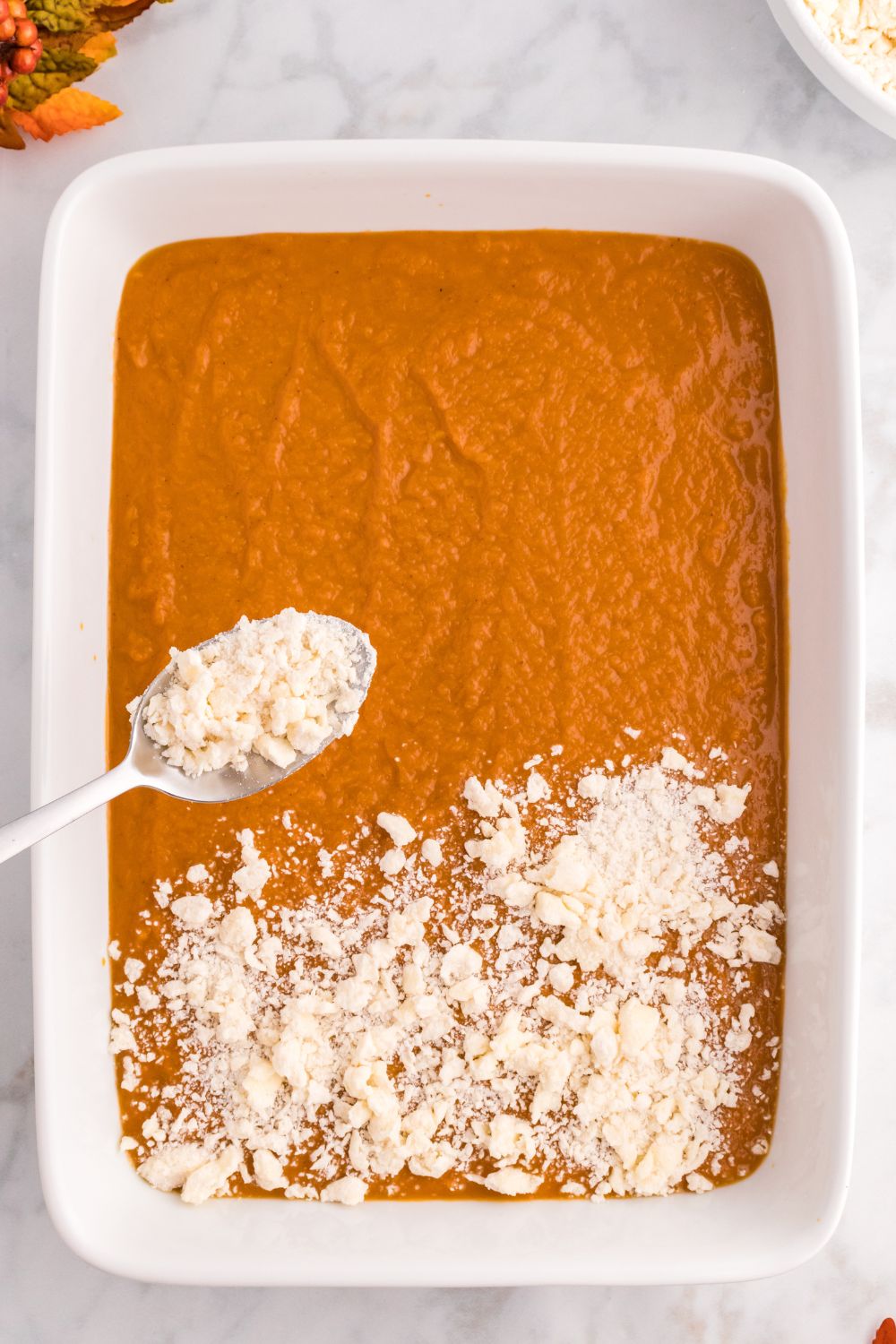 raw Pumpkin Pie Cake with a sprinkle of crumble going on top of cake with a spoon 