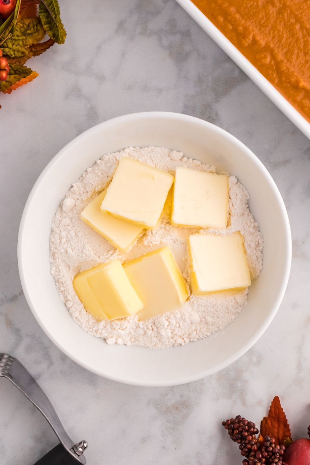 butter and flour in a bowl sitting on table with raw cake to the side in pan
