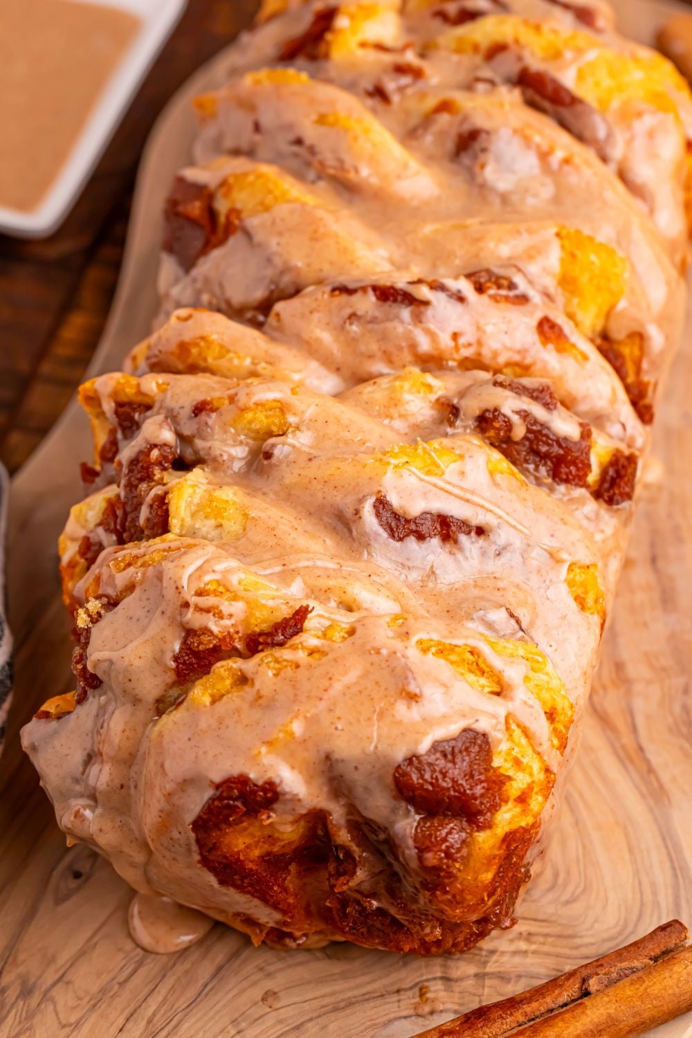 Pumpkin Pie Pull Apart Bread on a cutting board with glaze on side 