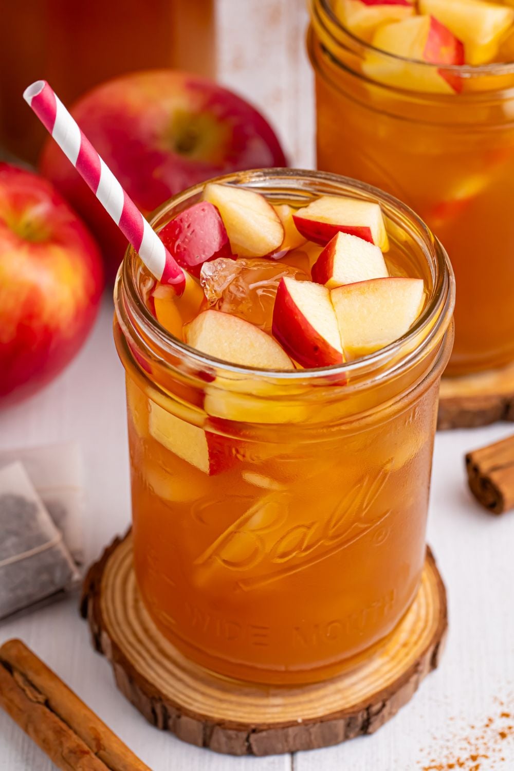 Apple Cider Iced Tea on table with a wooden cutting board under it and a straw sticking out the side