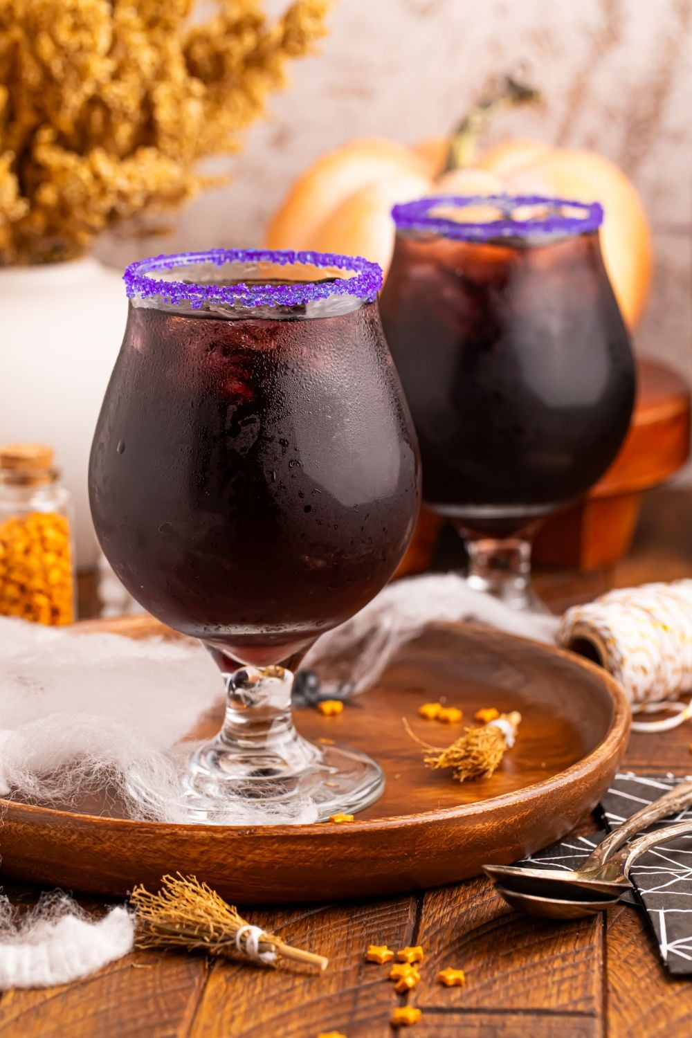 Witches Brew Cocktails sitting on table with a bunch of Halloween decor on table for a spooky vibe
