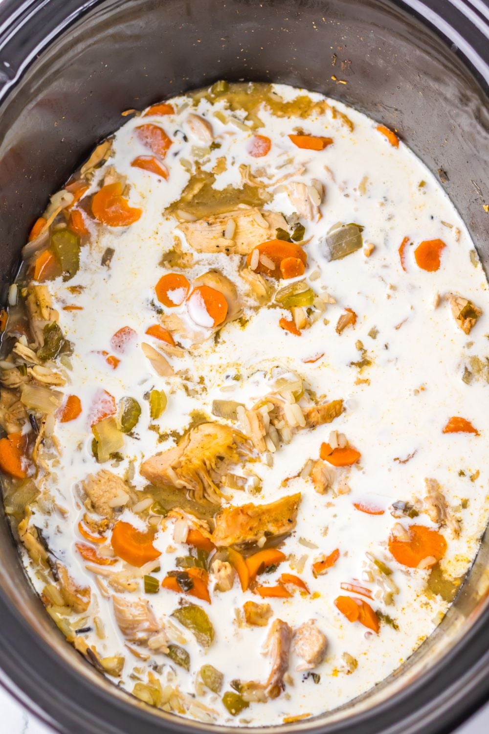 cream being poured into the slow cooker turkey soup