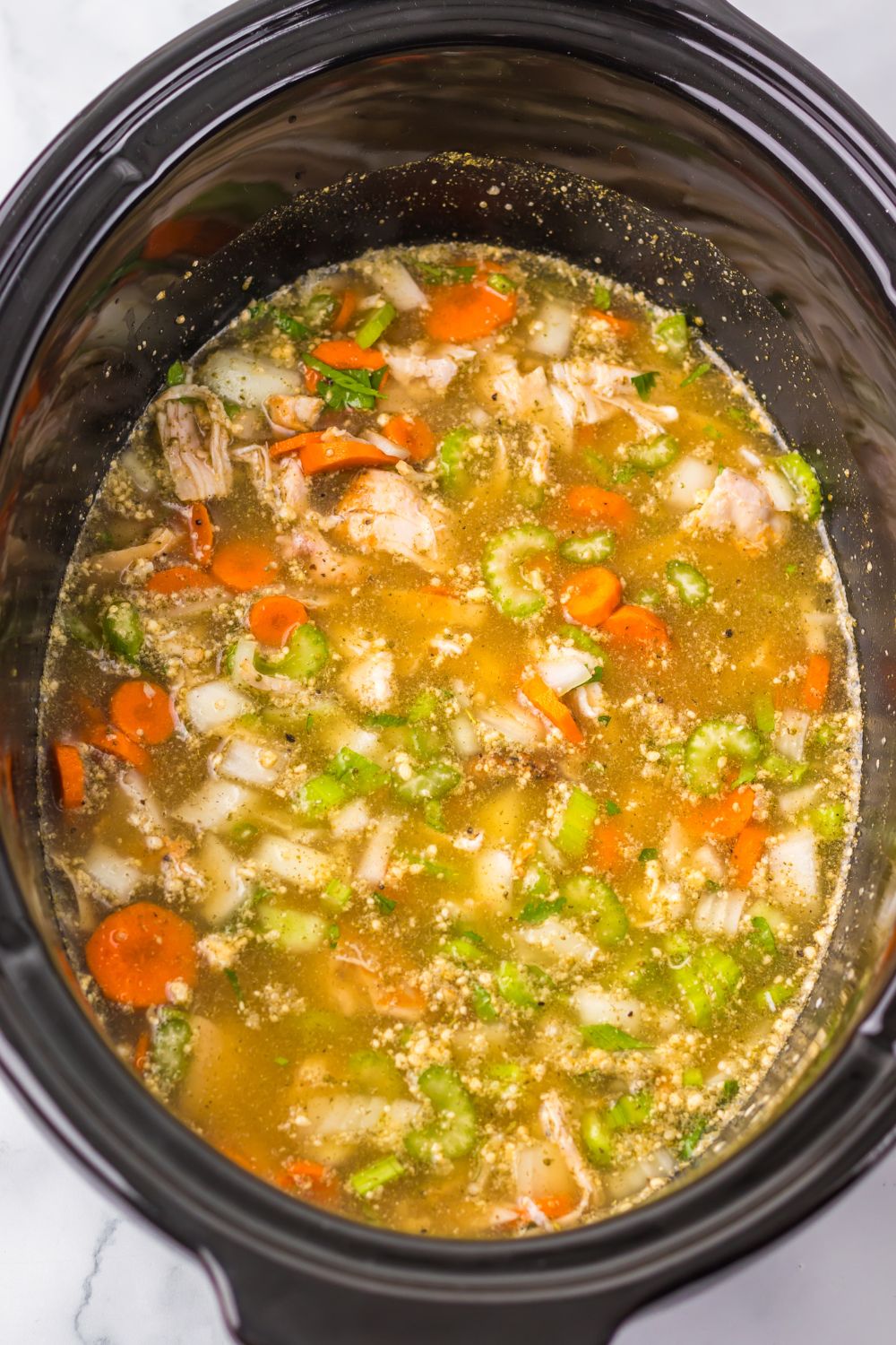 overhead look into slow cooker that is full of ingredients for the slow cooker turkey and rice soup
