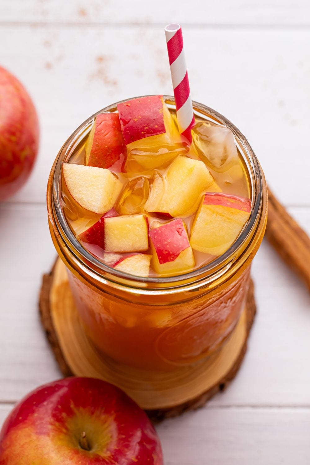 close up of mason jar with apple cider tea in it and a red and white straw sticking in it