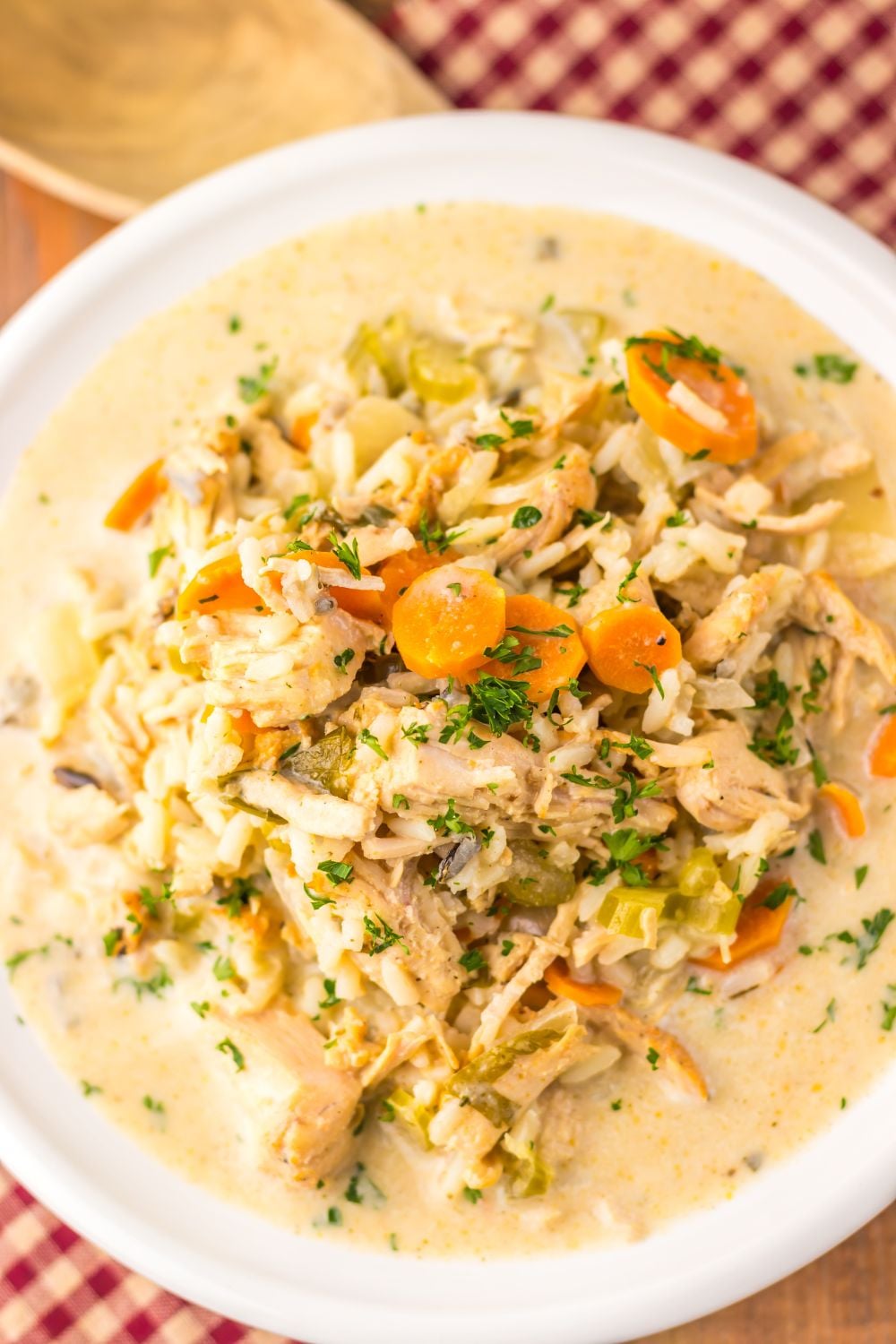 overhead look of turkey and rice soup in a bowl on table with a checkered cloth under the bowl