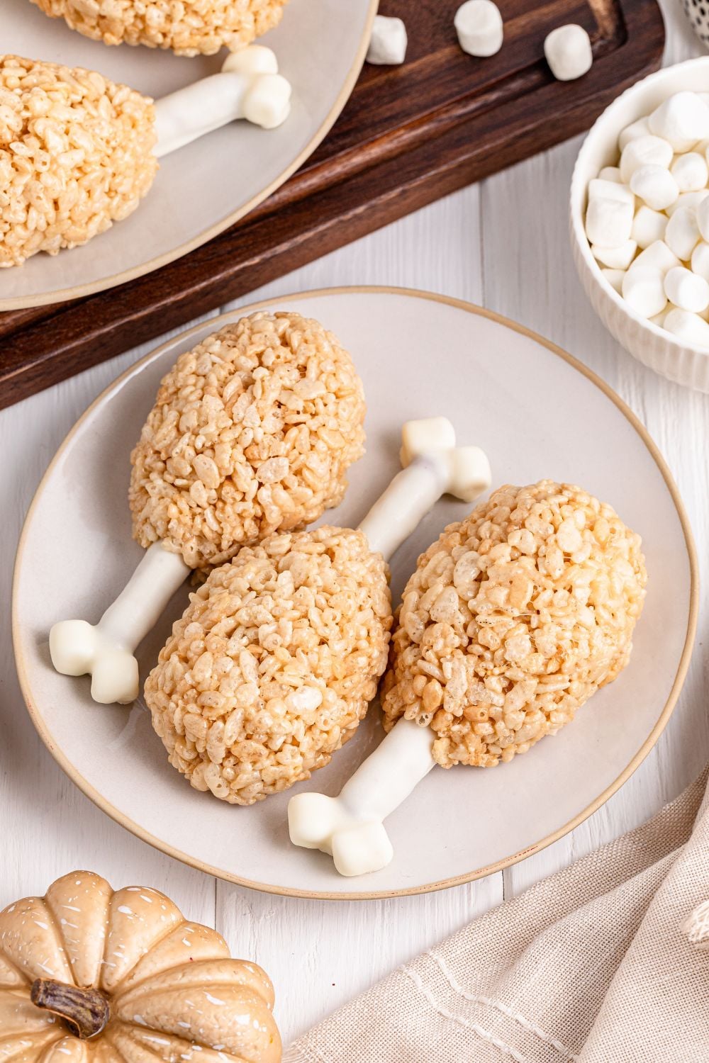overhead of rice krispies turkey legs on plate with bowl of marshmallows on the side