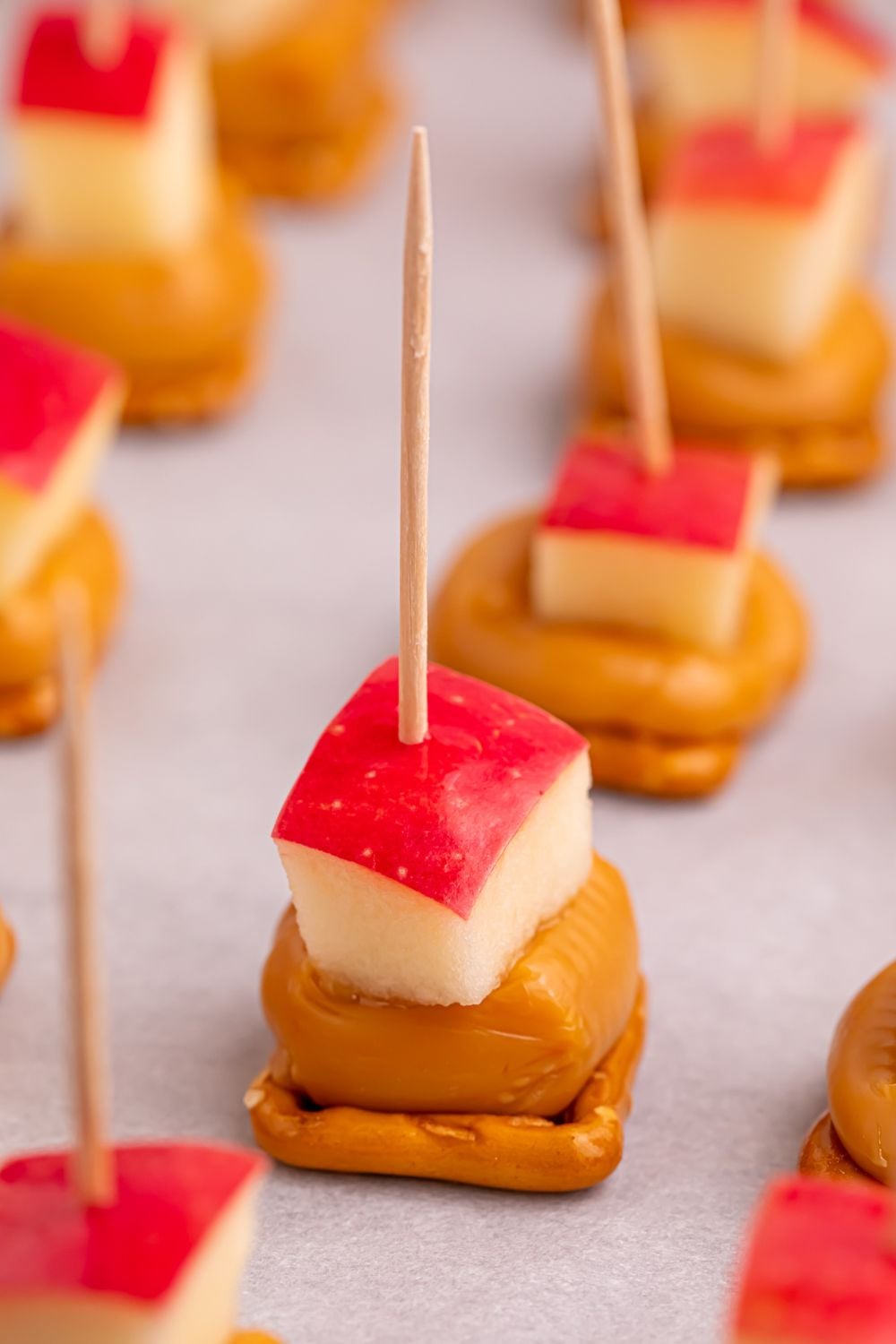 pretzel caramel bites with apples on top and toothpicks sitting on tray