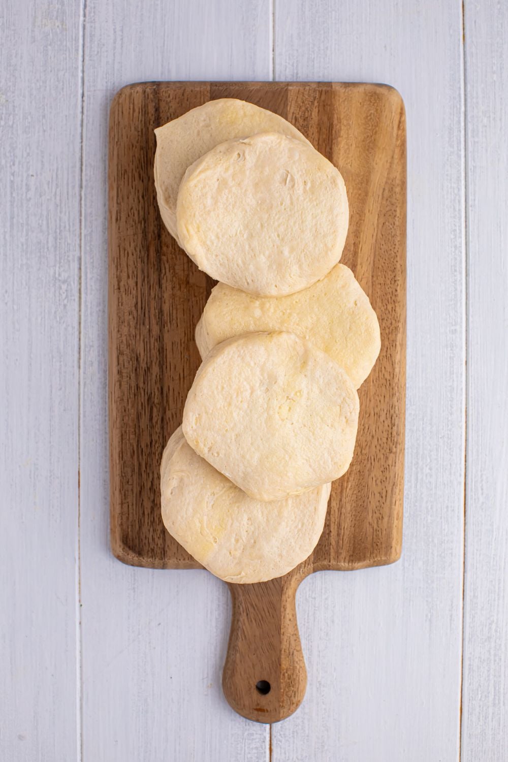 raw biscuit dough on a wooden cutting board sitting on table