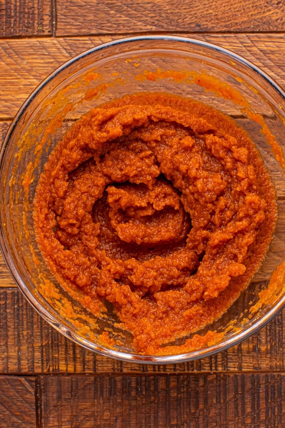creamy pumpkin puree in a glass bowl on wooden table