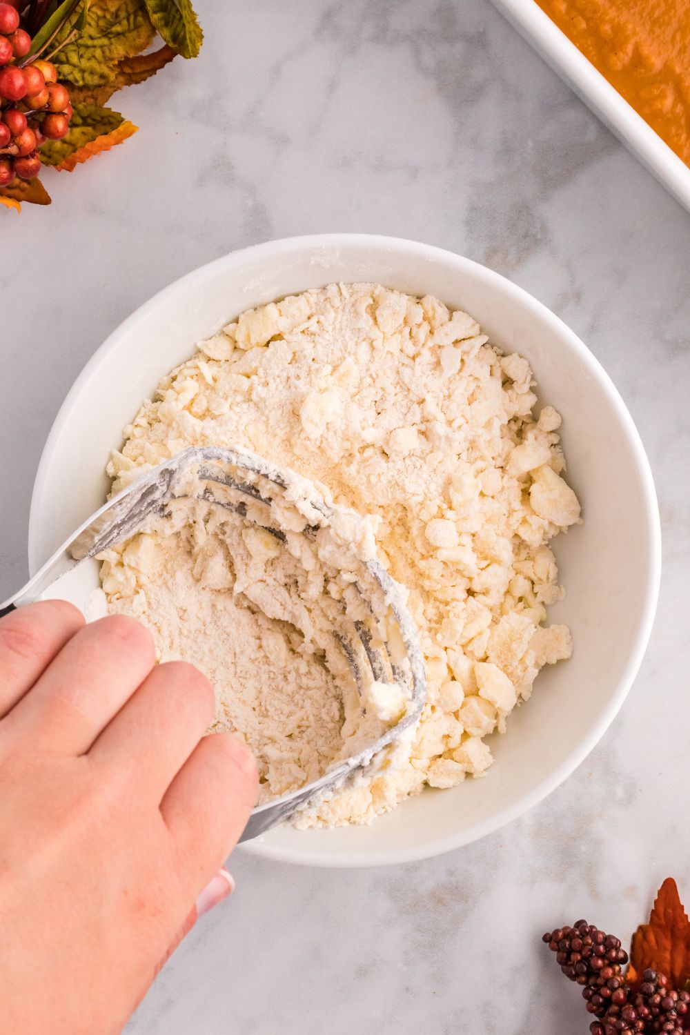 butter and cake mix getting crumbled together with a pastry cutting in a bowl 