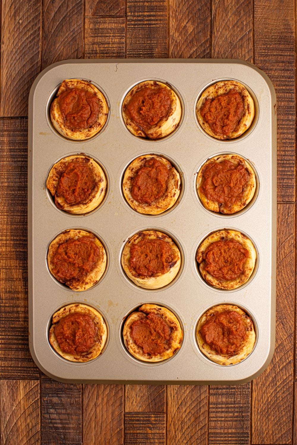 baked Pumpkin Pie Cinnamon Roll Cups in a muffin tin on table