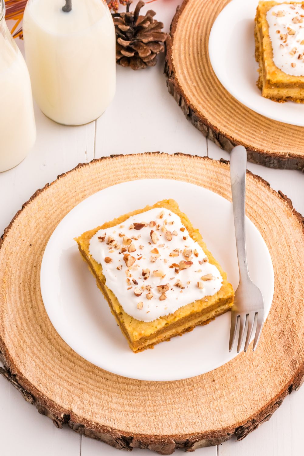 slice of pumpkin layered cake on a plate with glasses of milk on the side