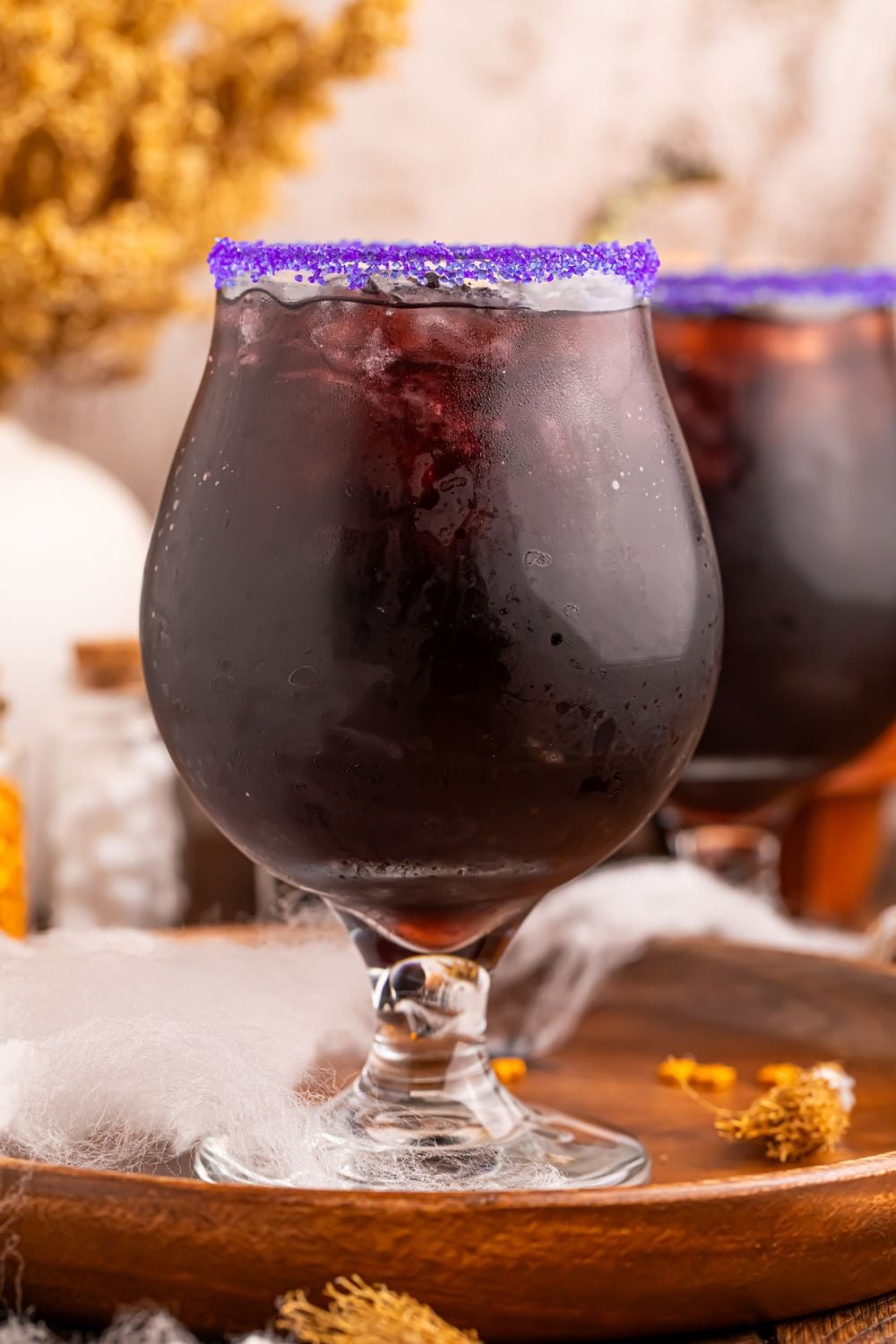 side view of glasses with a Witches Brew Cocktail in each of them sitting on a platter on table