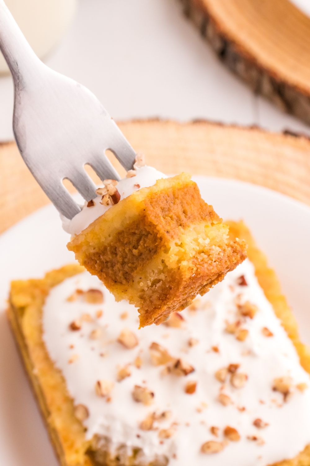 slice of Pumpkin Pie Cake on plate with a fork with a bite on it 