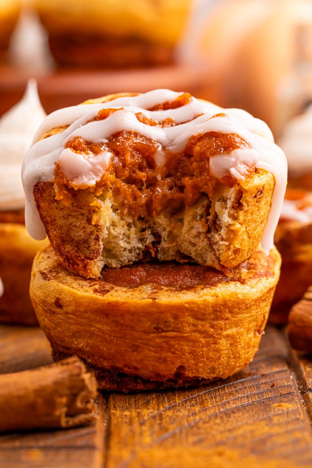 Pumpkin Pie Cinnamon Roll Cups stacked on top of one another with one with a bite taken out of it