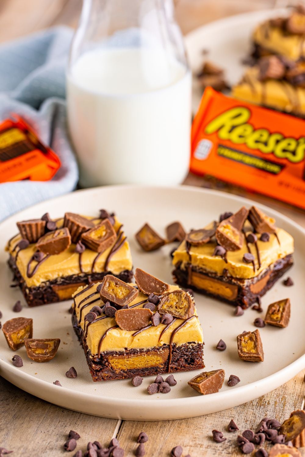 Reeses Stuffed Brownies on a plate with a jug of milk and Reeses package in the background