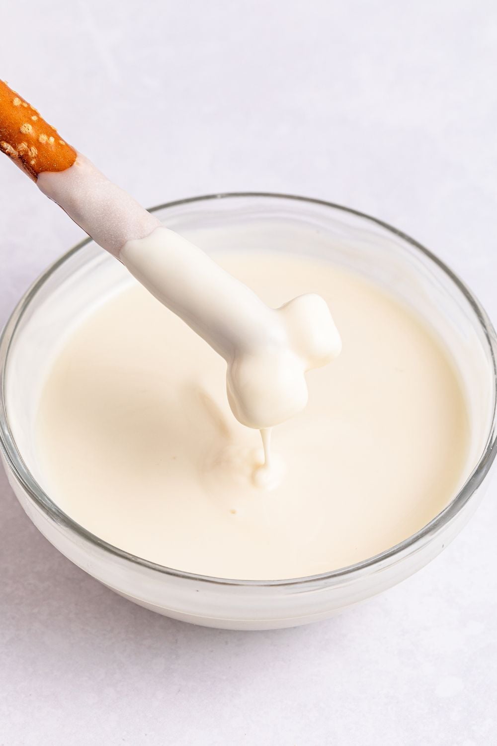 melted white chocolate with a pretzel being dipped in it