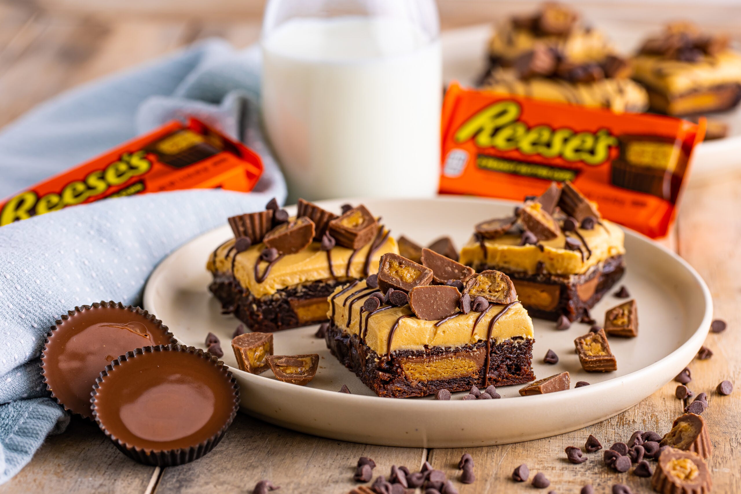 Reeses Stuffed Brownies on a plate with a jug of milk and Reeses package in the background