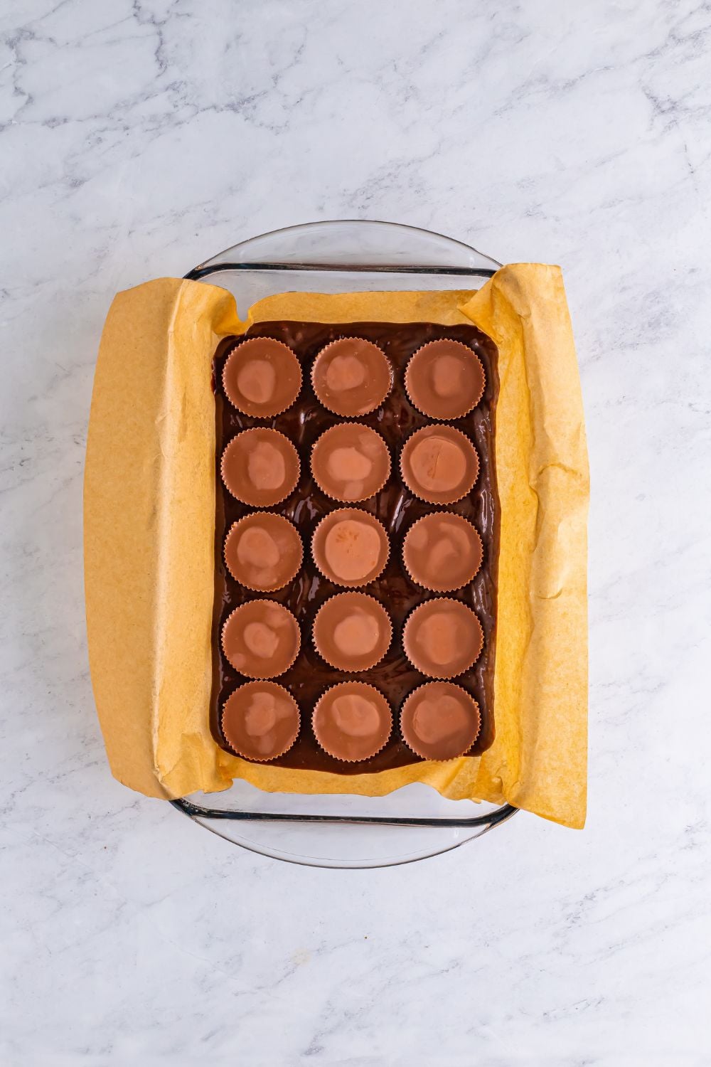 overhead look of brownie mix in a casserole dish topped with Reese's peanut butter cups