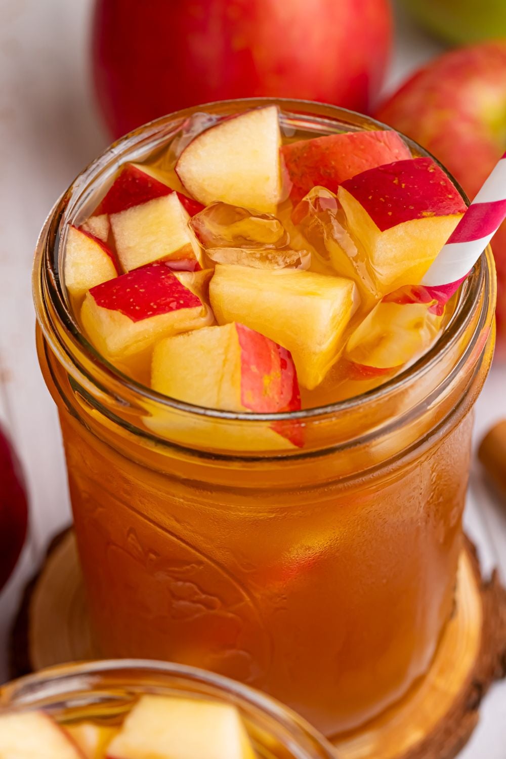 tea cider in a glass with diced apples and ice in the glass