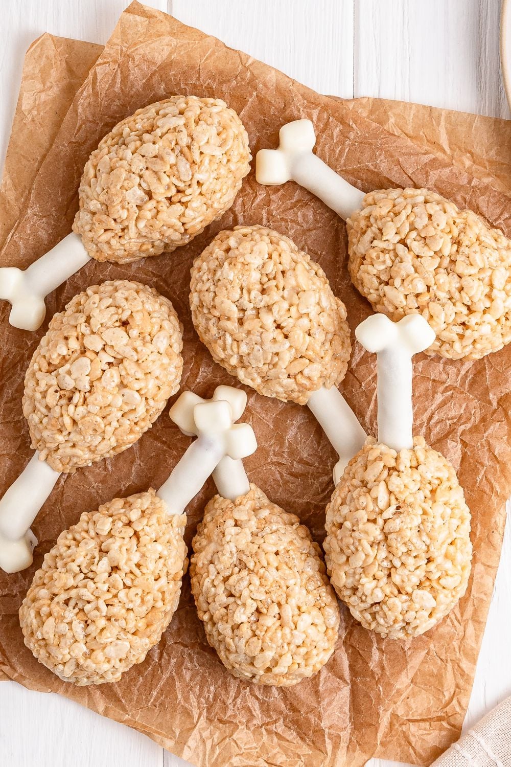 Rice Krispie Treat Turkey Legs spread on parchment paper sitting on a white table