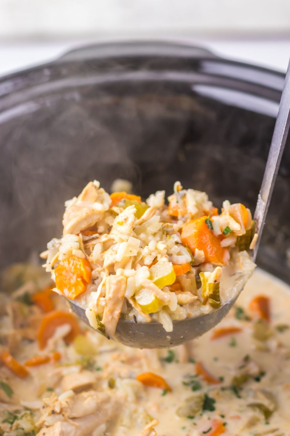 Slow Cooker Turkey & Rice Soup on table with a metal spoon scooping the soup out of the slow cooker