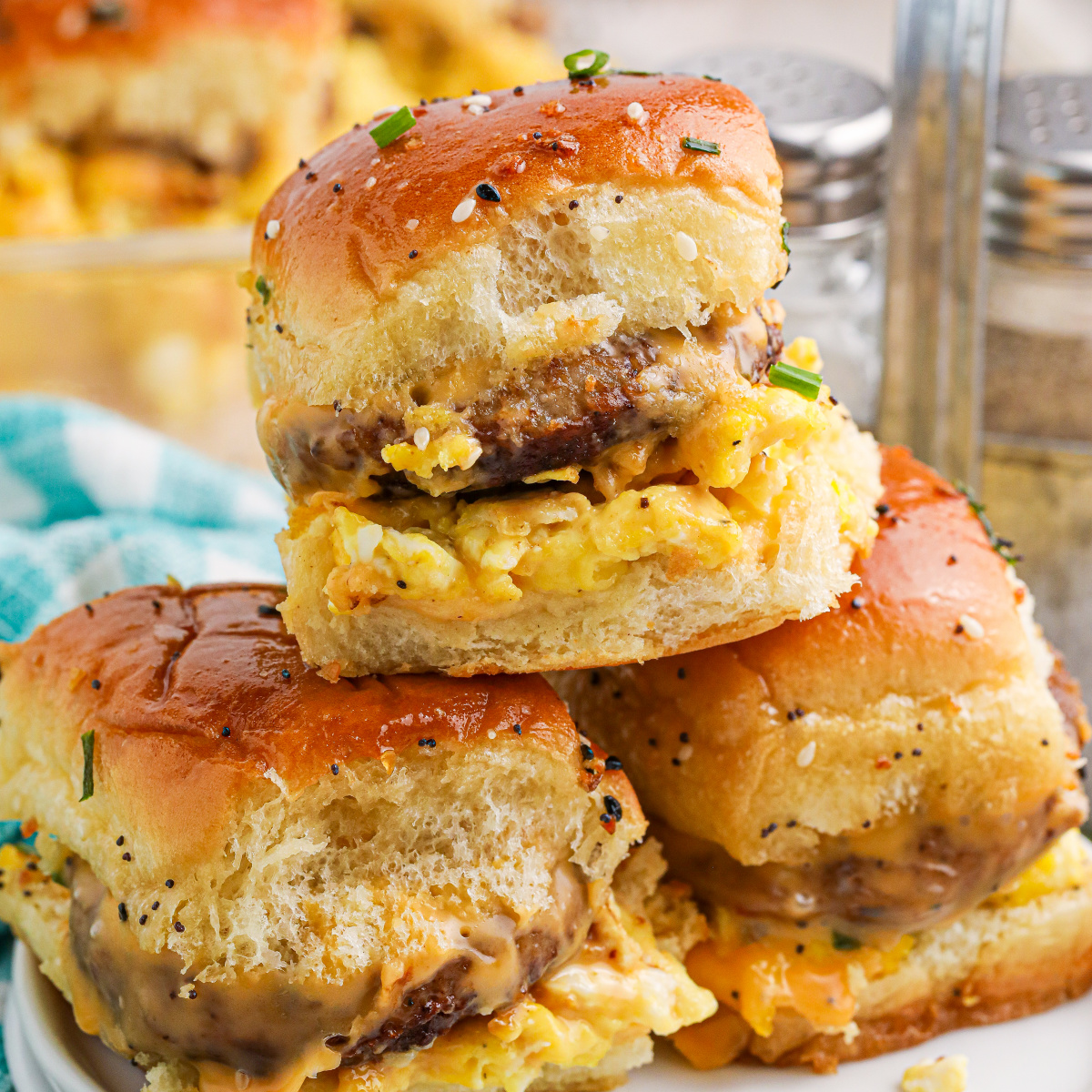 Fully Loaded Cheesy Breakfast Sliders with Sausage stacked on a white plate