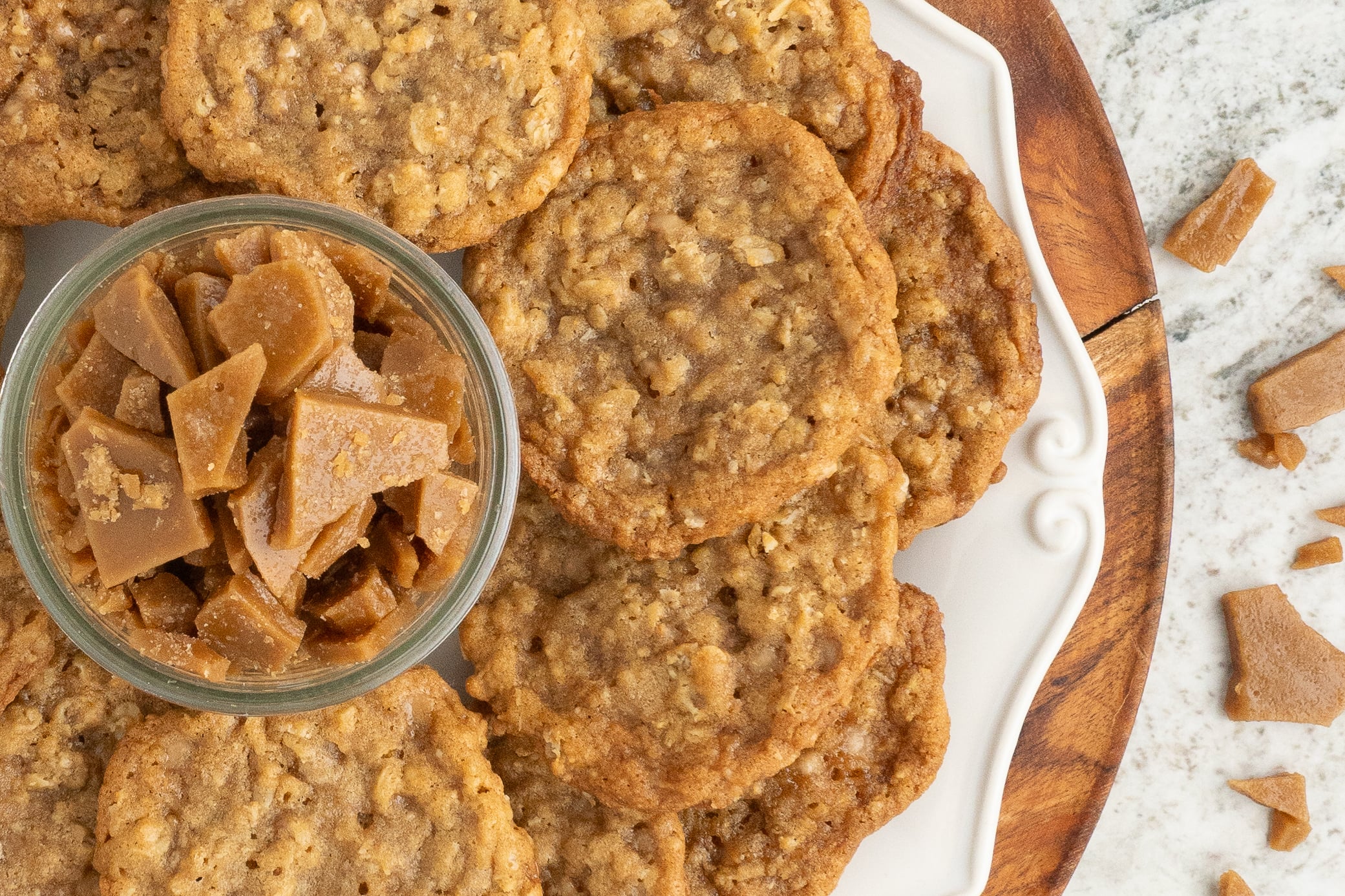 Oatmeal Toffee Cookies spread on tray with a bowl of toffee bits in the center 