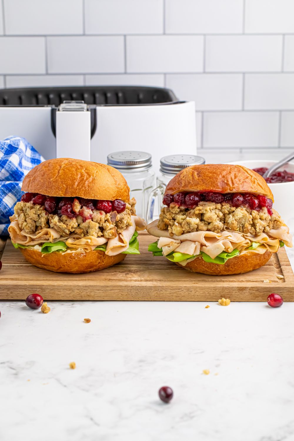Leftover Turkey Sandwiches sitting on a cutting board with an air fryer behind it on the counter 