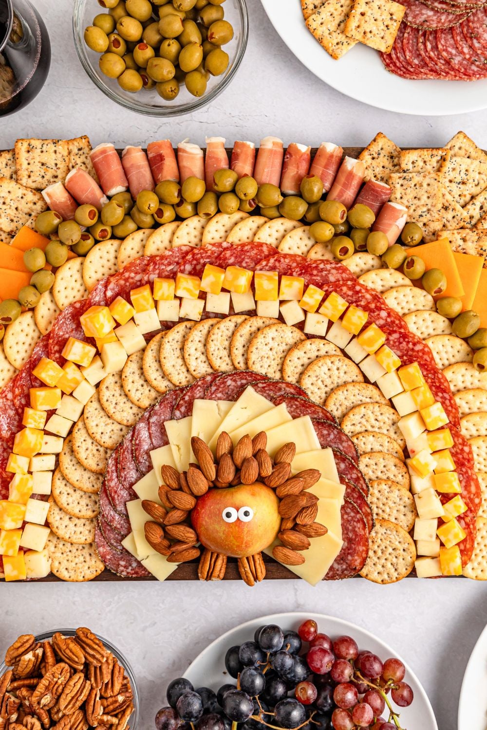Turkey Snack Board on table with bowls of olives, plate of grapes and more around the snack board