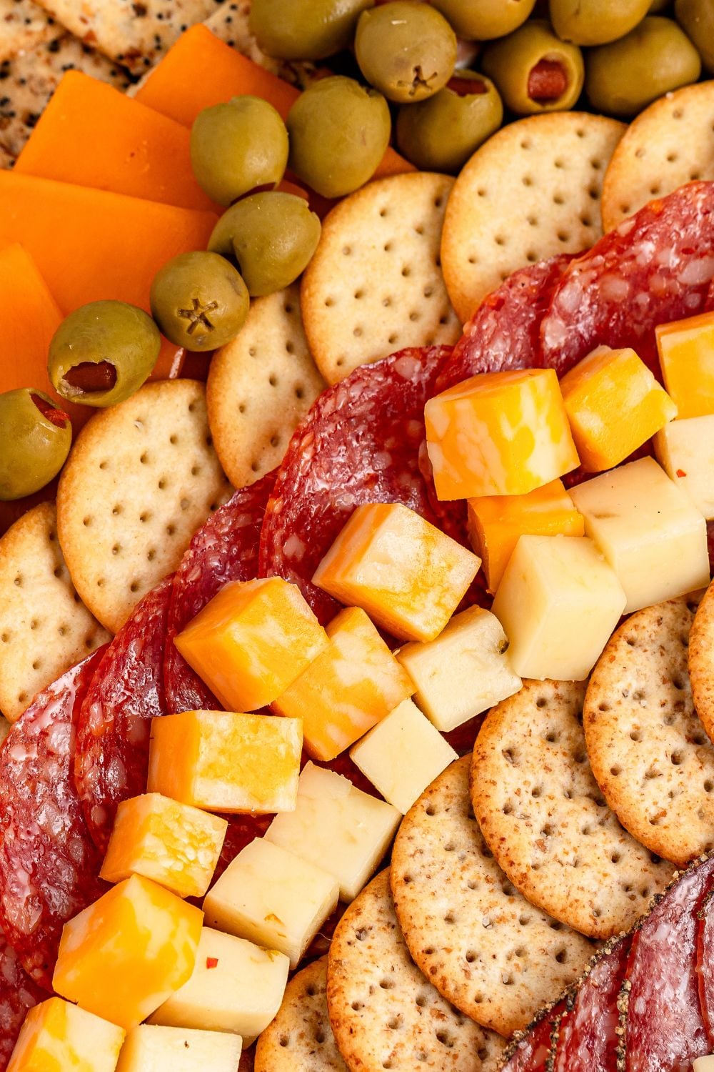 cheese, crackers, meats all in rows on table for a charcuterie board