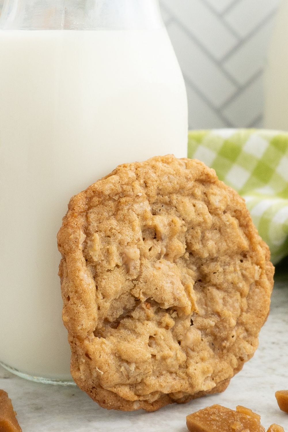 Oatmeal Toffee Cookie on side of a glass of milk on table 