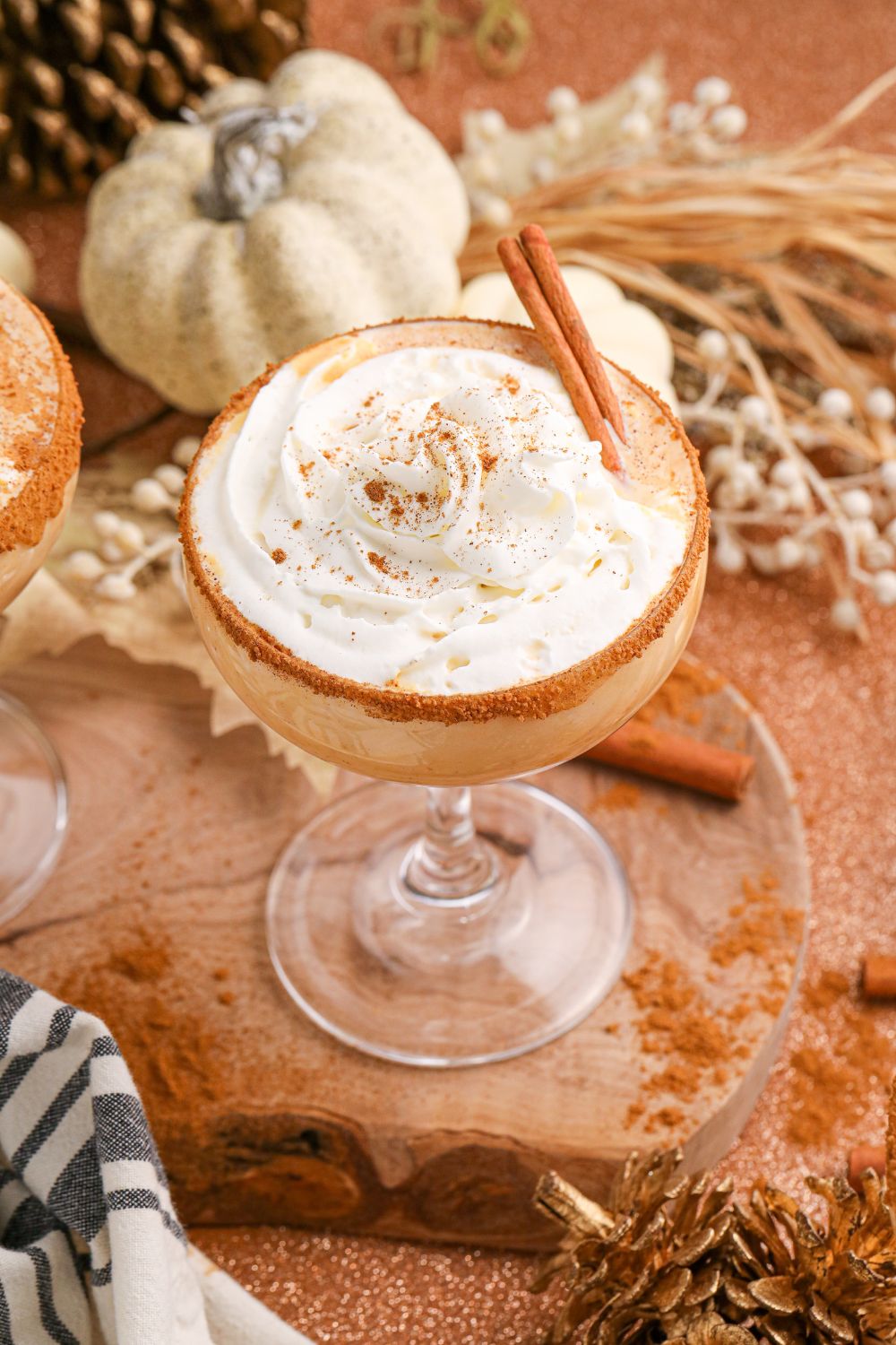 pumpkin martini in a glass sitting on a table with fall decor around it