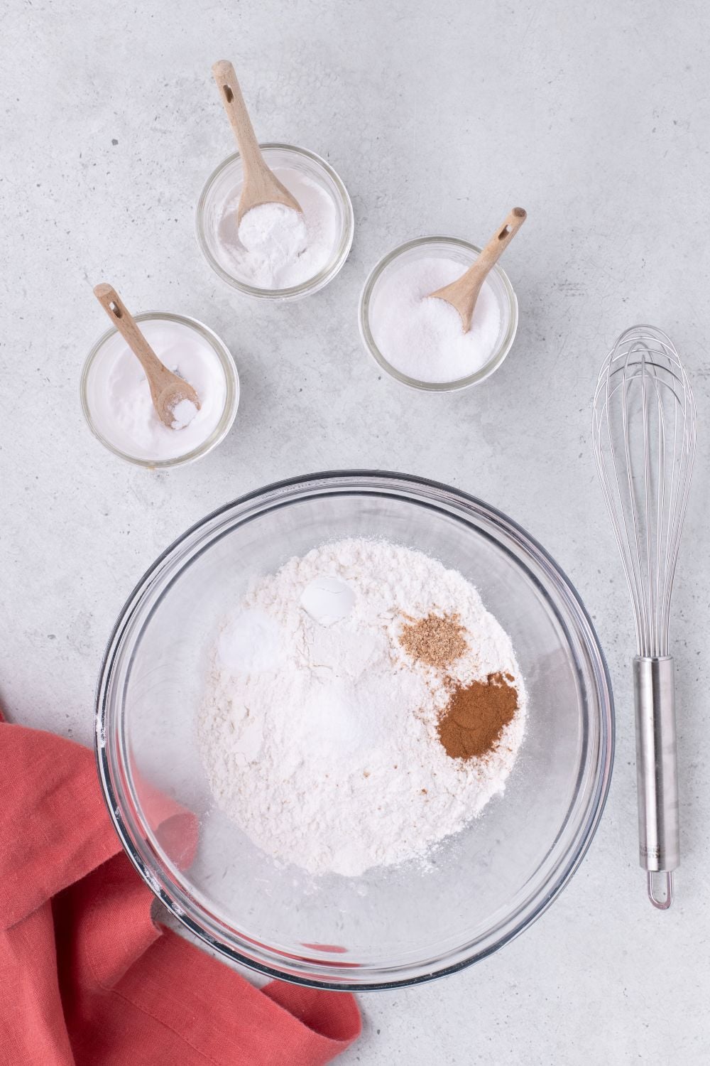 dry ingredients in a large bowl sitting on table with whisk to the side