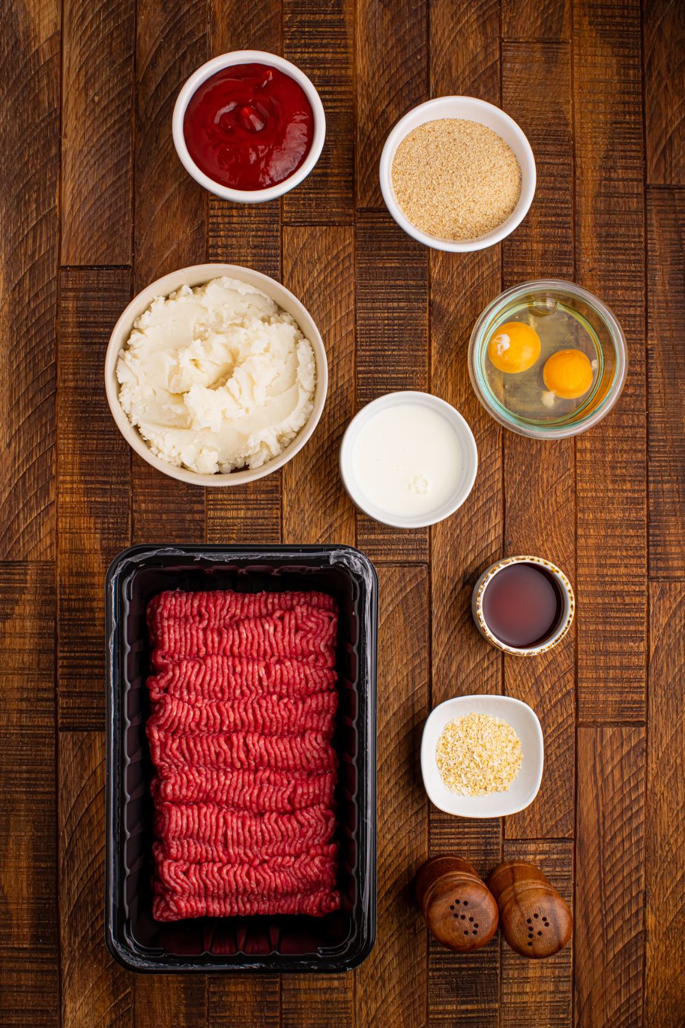 ingredients to make Meatloaf Cupcakes on table: raw beef, egg, milk, breadcrumbs, ketchup, and more