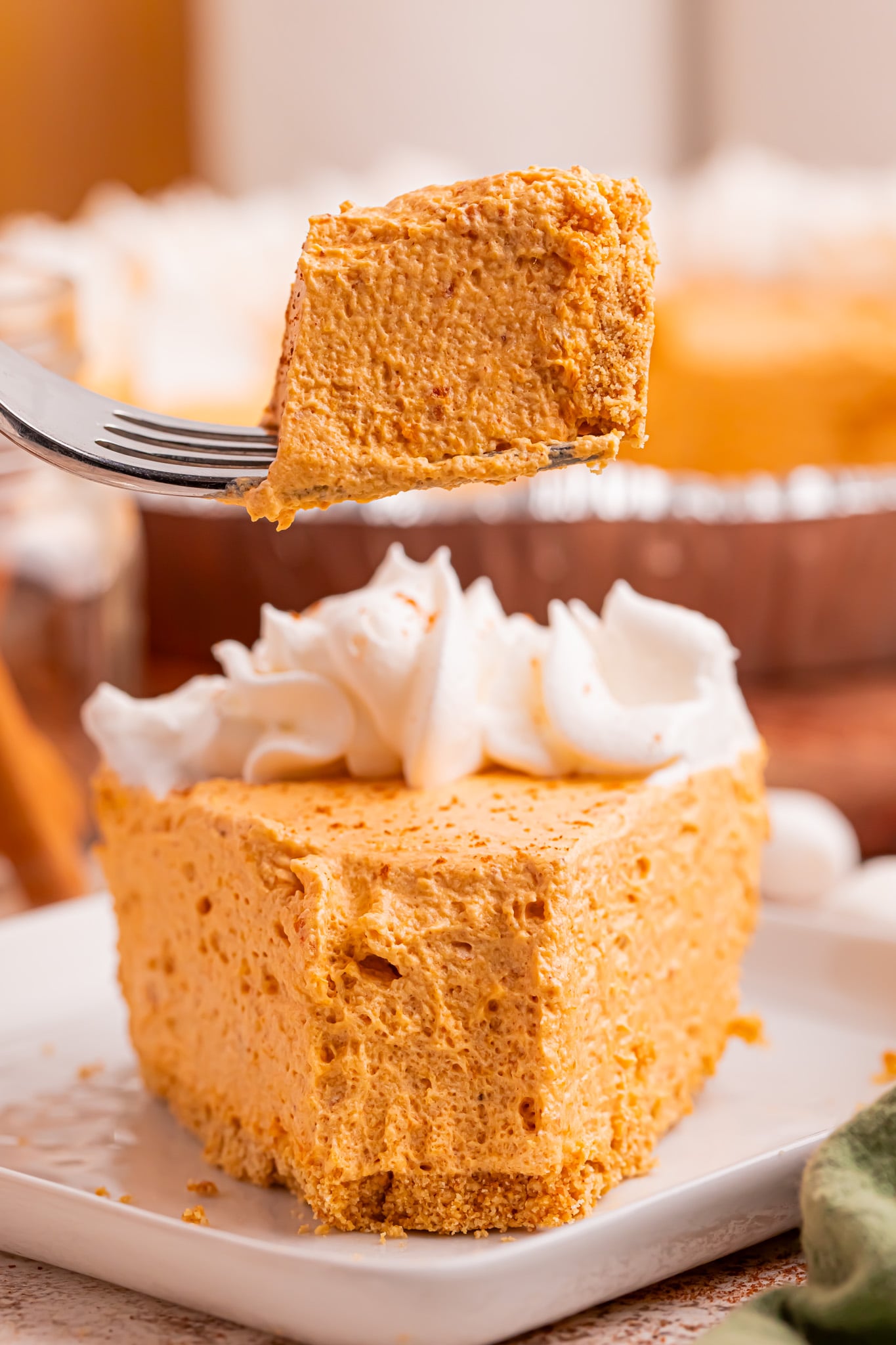 Marshmallow Pumpkin Pie slice on plate with a fork with a bite on it above plate
