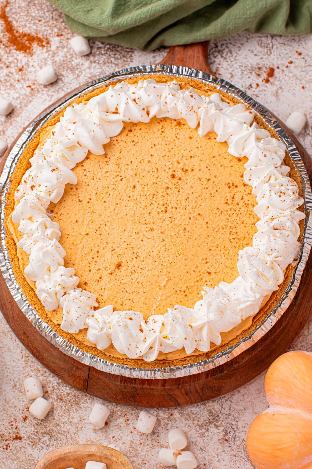Marshmallow Pumpkin Pie on table with fall decor around it and mini marshmallows