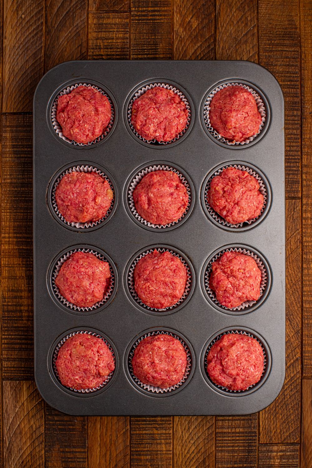 raw meatloaf in a muffin tin tray sitting on table