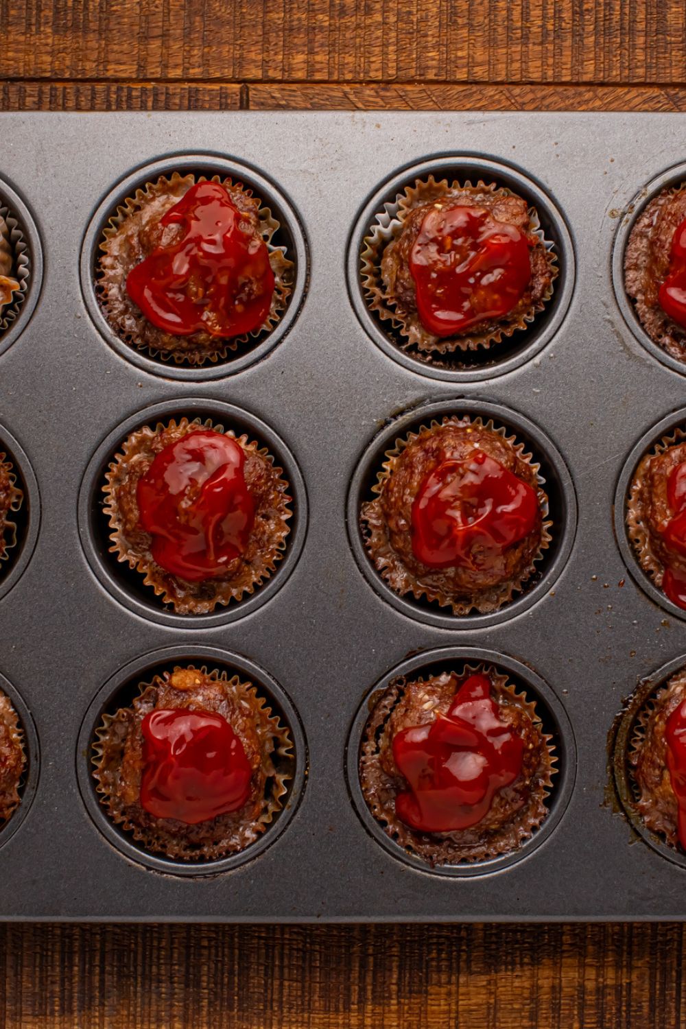 Meatloaf Cupcakes in a muffin tin with ketchup on top of each meatloaf