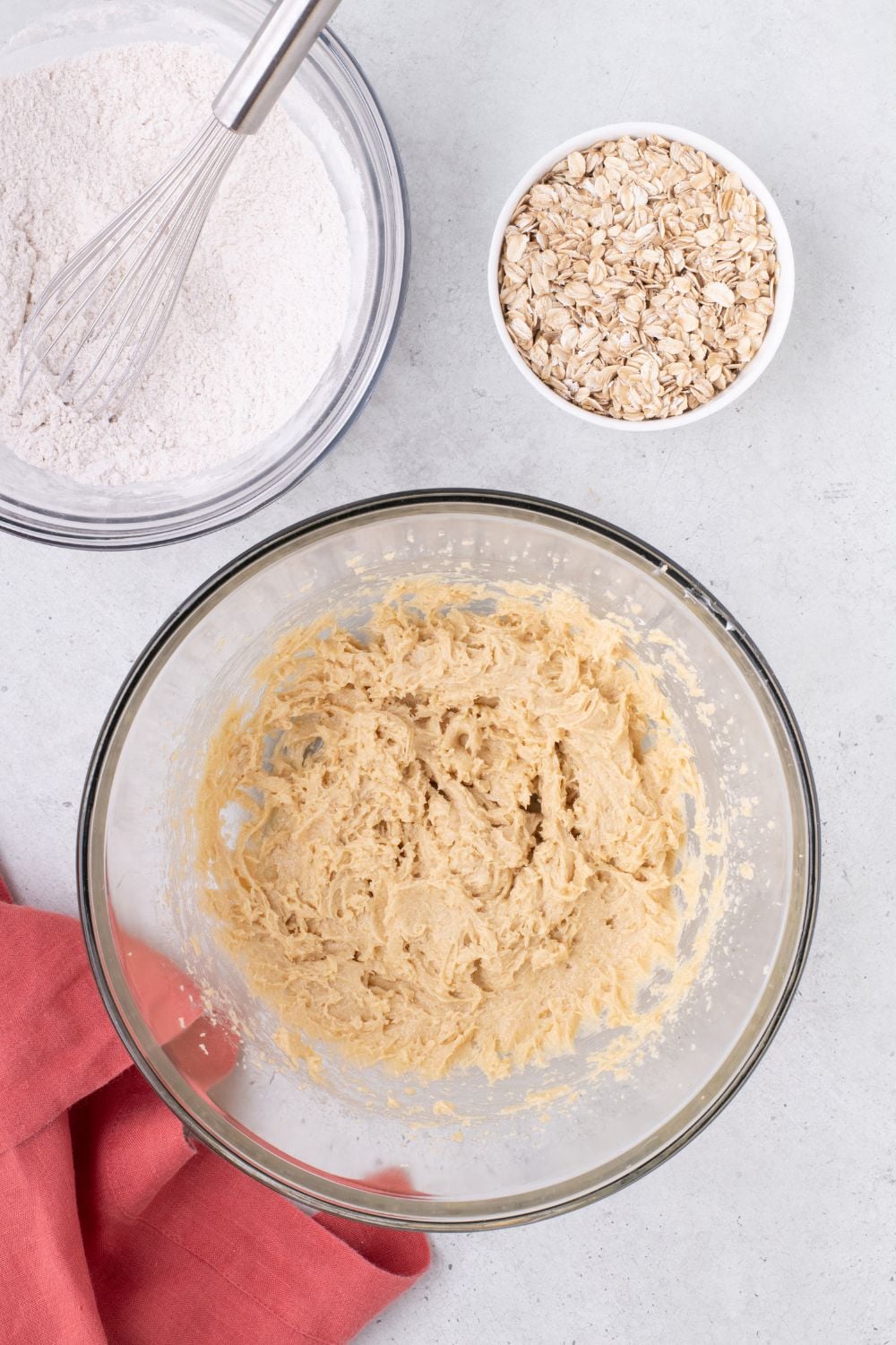cookie batter on table with oats and flour mixture in separate bowls on table