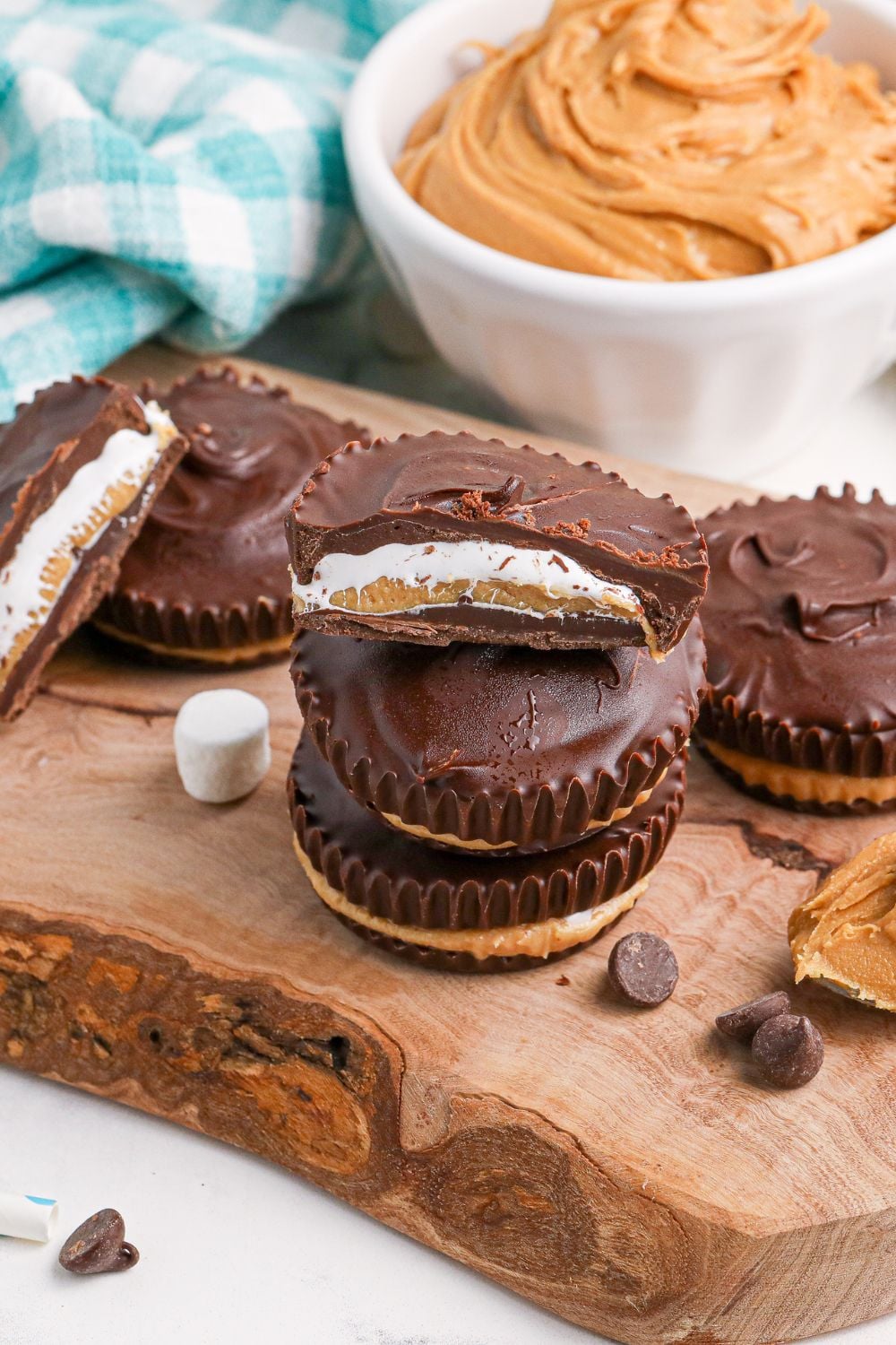 Peanut Butter Marshmallow Cups on wooden table with marshmallows and chocolate chips around cups on table