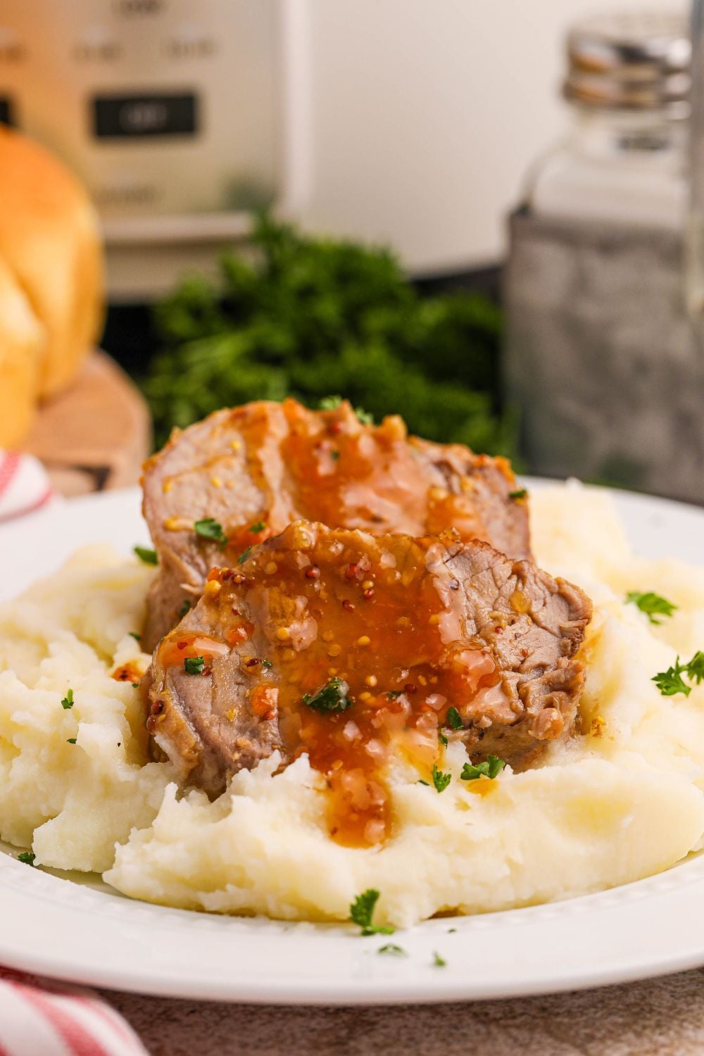 pork tenderloin apricot glazed sitting on top of mashed potatoes on a plate