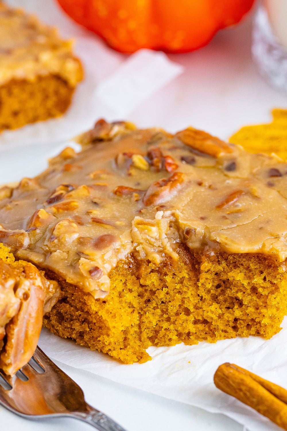 Pumpkin Snack Cake with Praline Icing on table with a few bites taken out of the slice of the cake