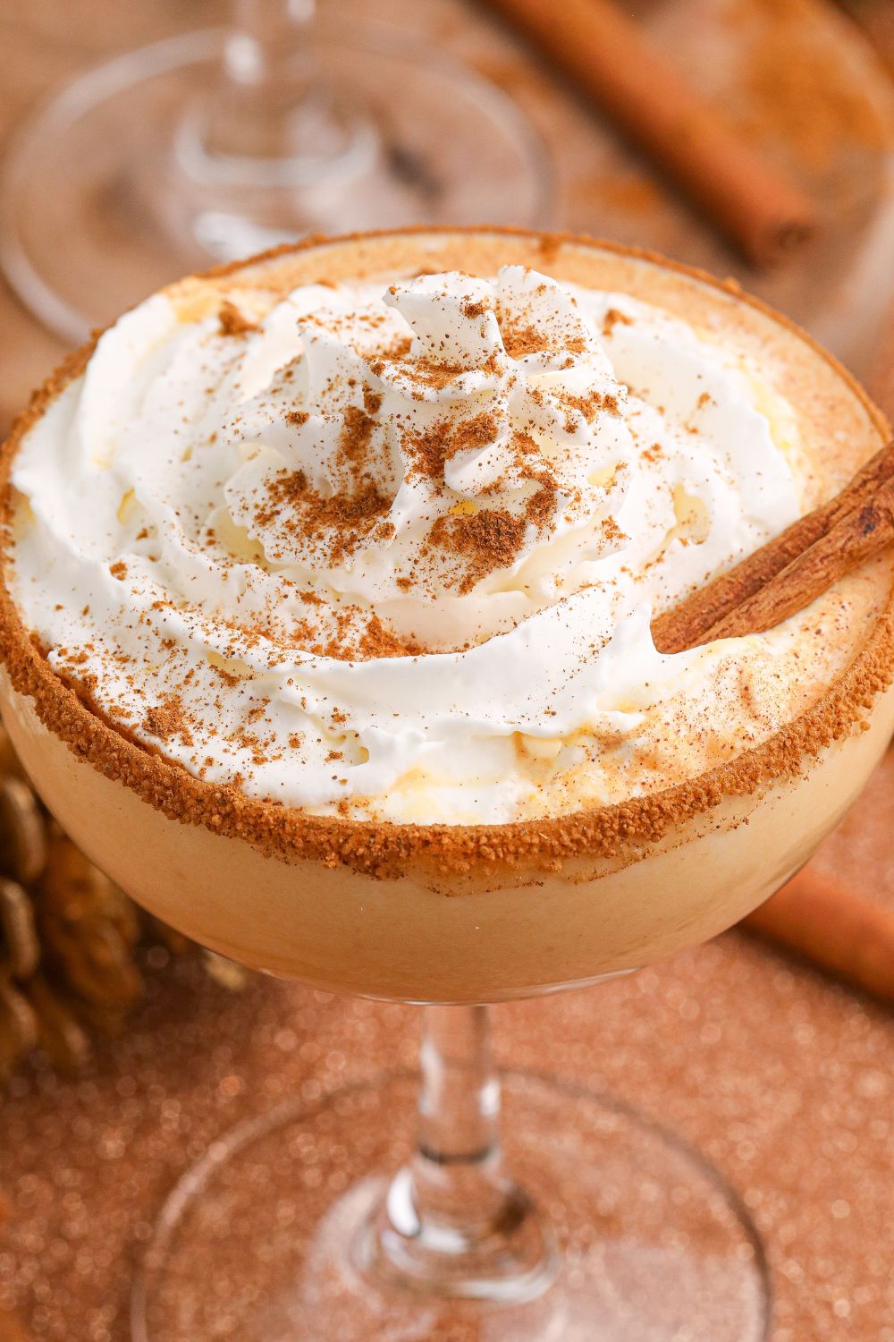 close up of a pumpkin martini in glass with whipped cream on top