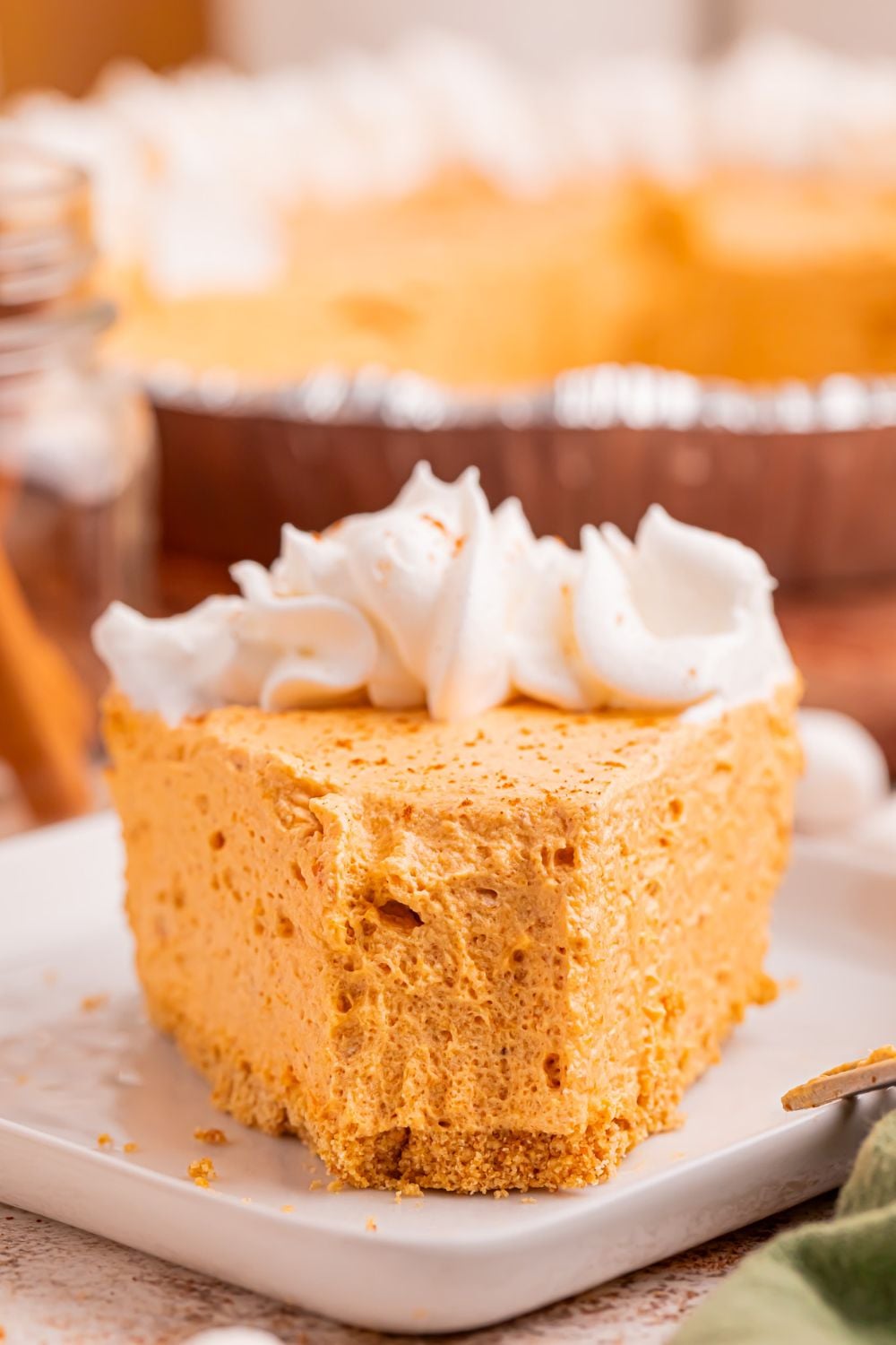 front view of a slice of marshmallow pumpkin pie on table with a fork full taken off the plate
