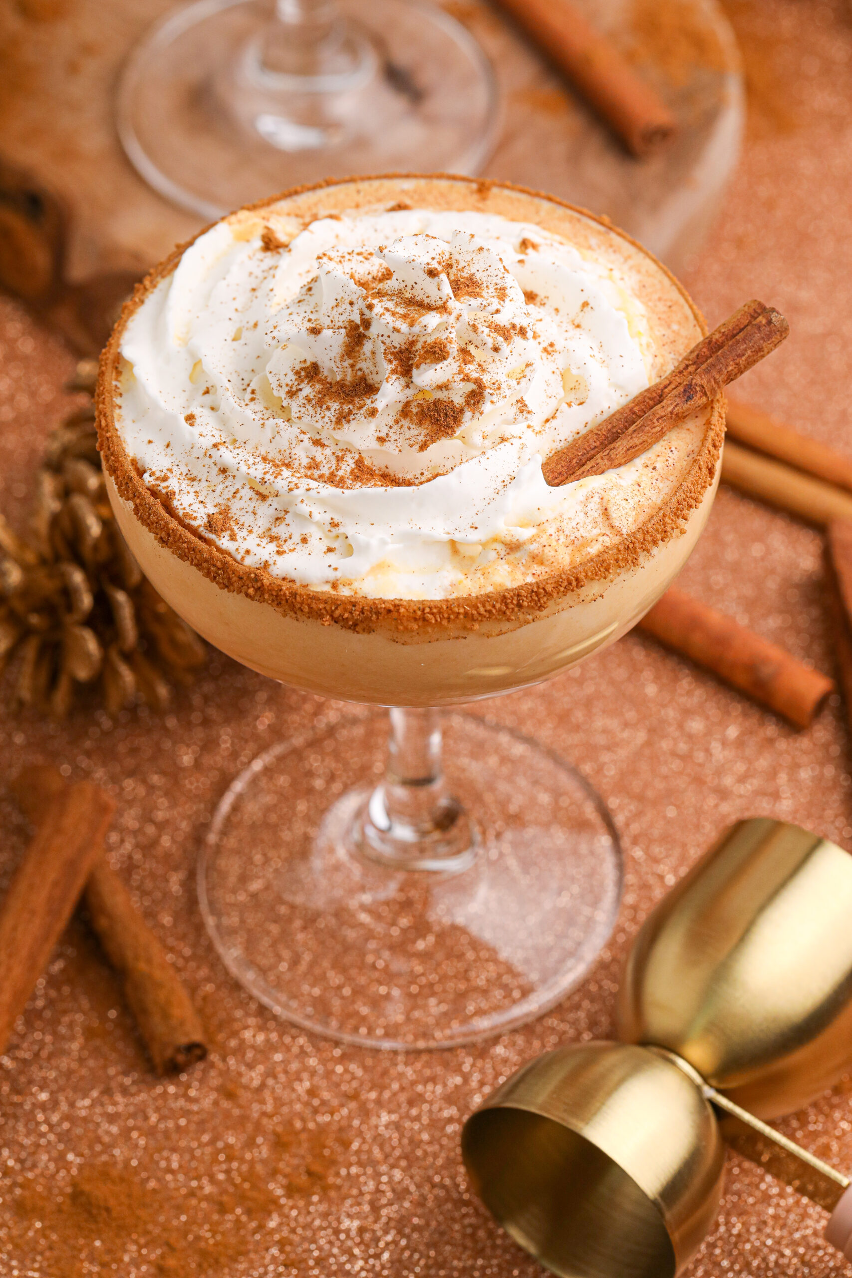 Pumpkin Pie Martini in a glass on a table decorated for a holiday with cinnamon stick on the side of glass