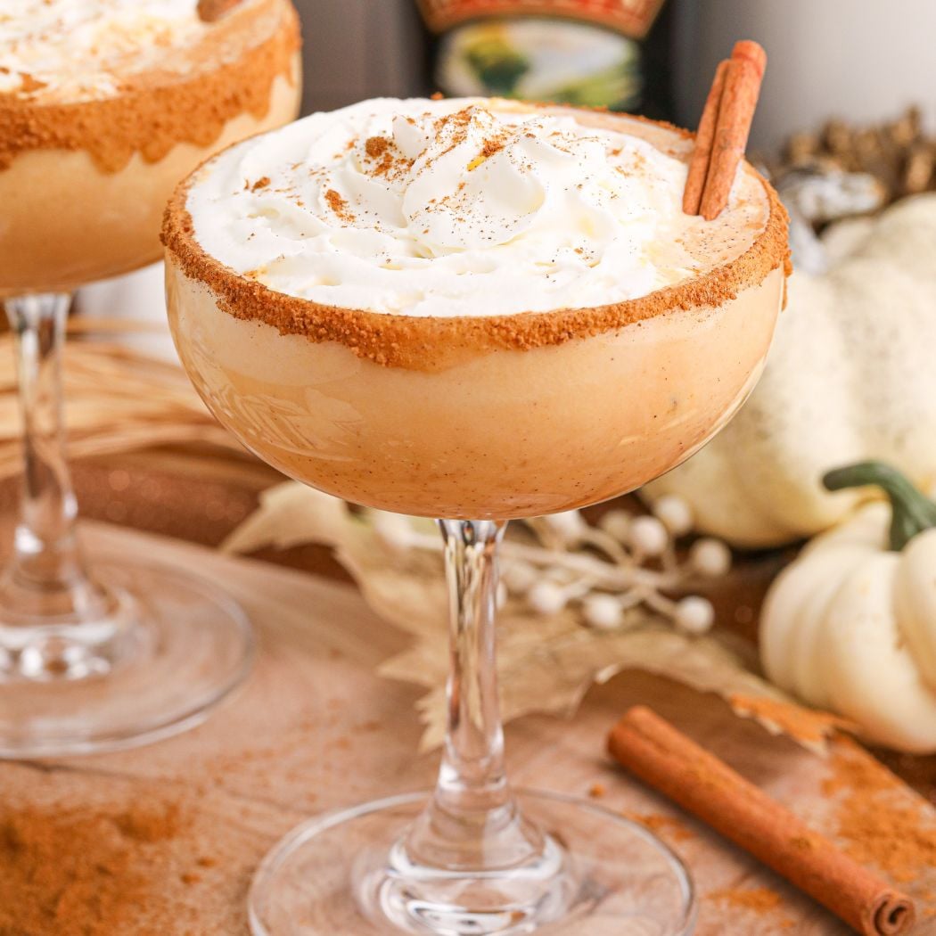 Pumpkin Pie Martini in a glass on a table decorated for a holiday with cinnamon stick on the side of glass