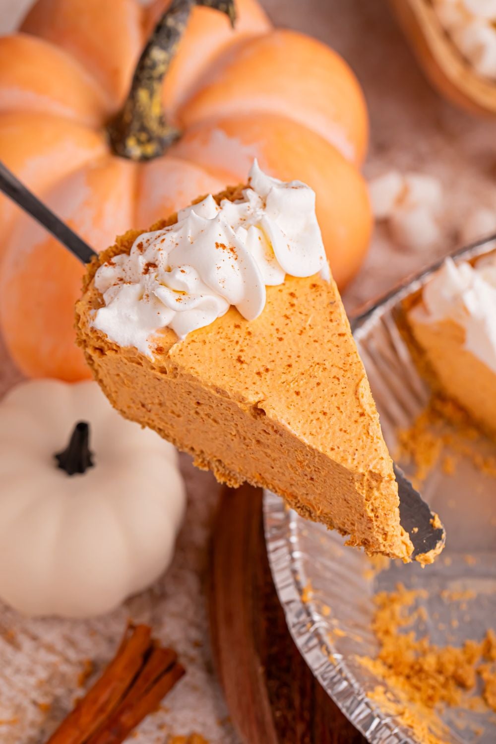 spatula with slice of pumpkin pie on it above the pie plate with the rest of the pie